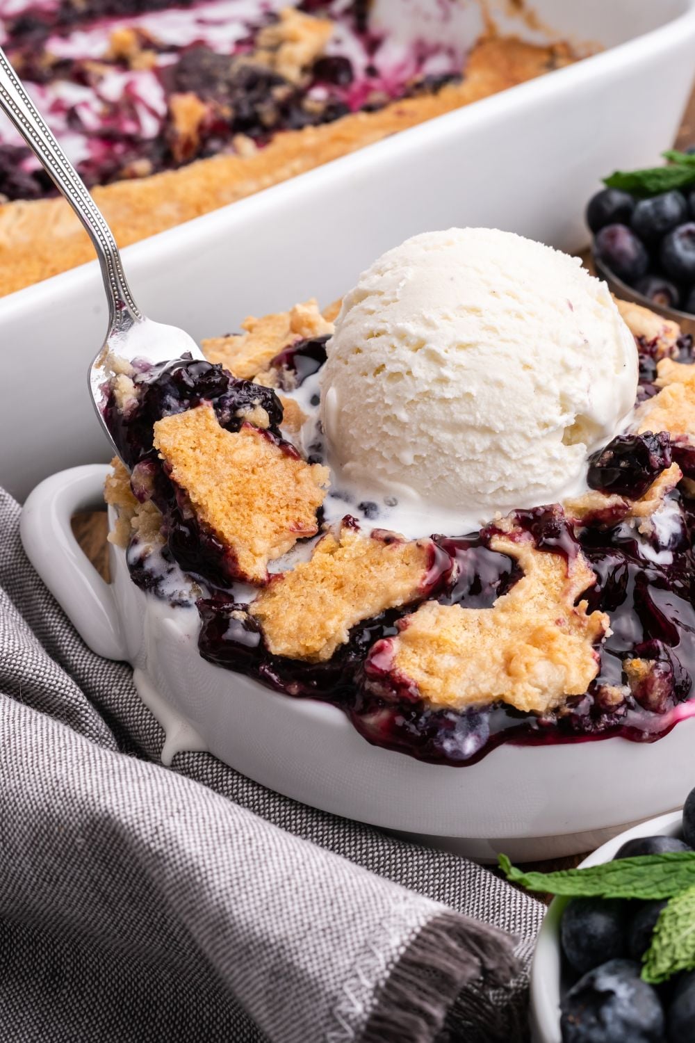 white bowl full of Blueberry Dump Cake with a spoon scooping out of the edge