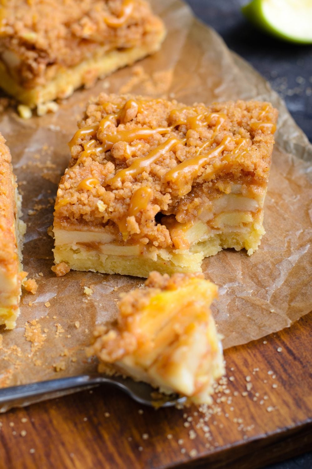 Caramel Apple Pie Bar sliced into a square with a bite taken out and placed on a spoon in front of the bar