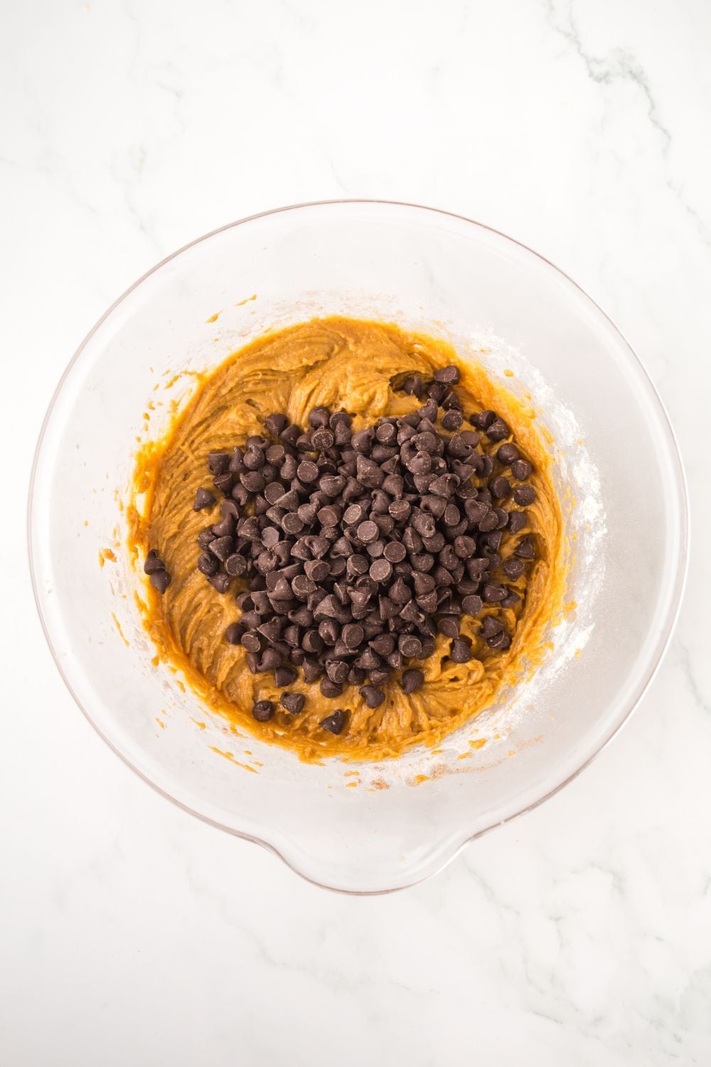 pumpkin bar batter in a glass bowl topped with chocolate chips sitting on a white table