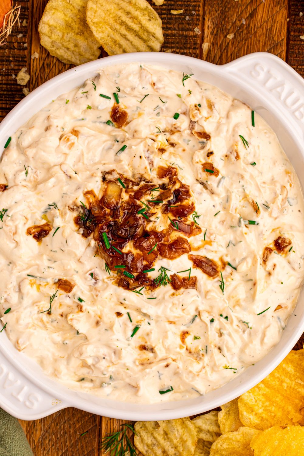 Caramelized Onion Chip Dip in a white bowl with chips around the table 