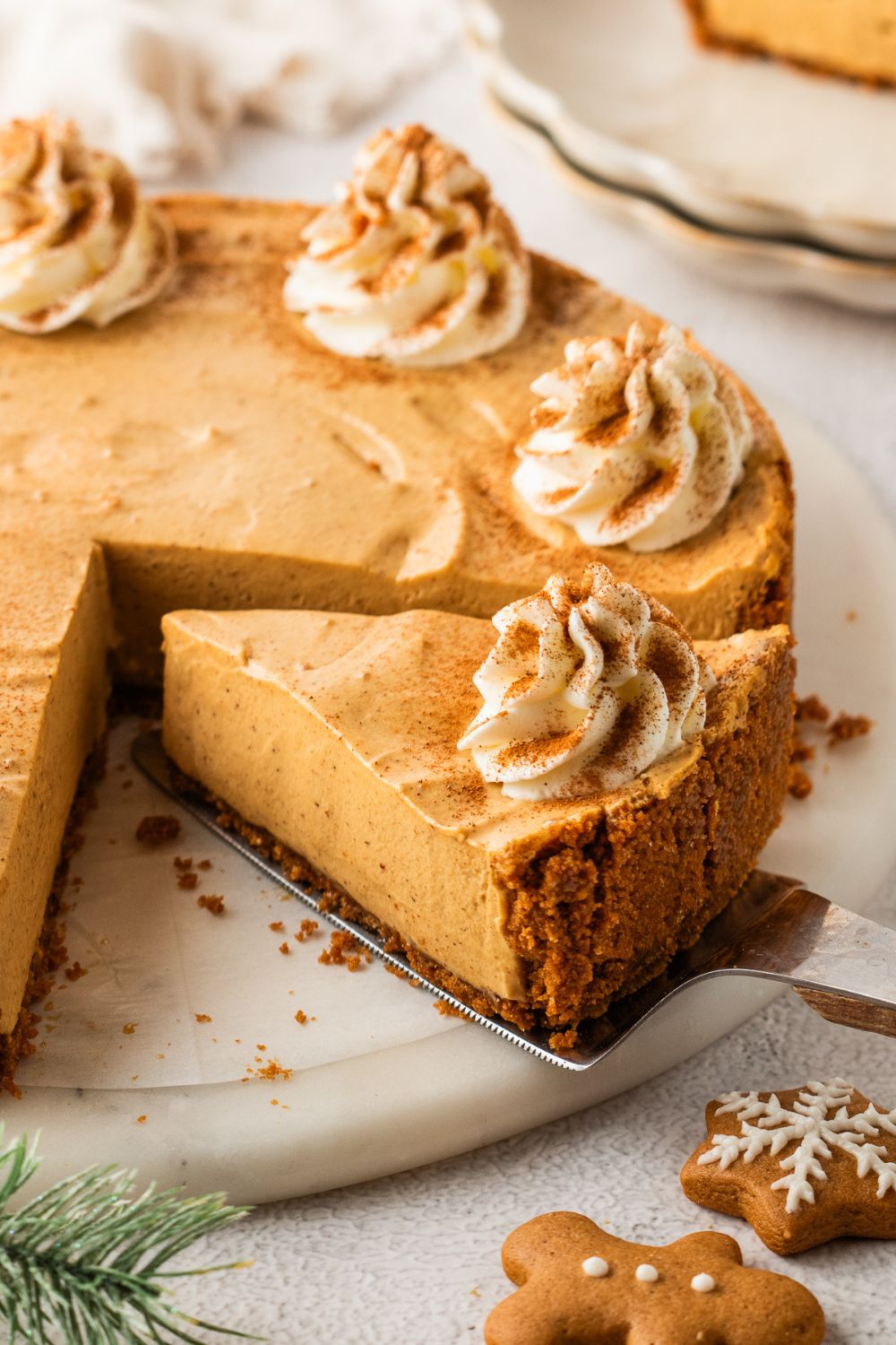 No Bake Gingerbread Cheesecake with a slice cut and being lifted up with a spatula 