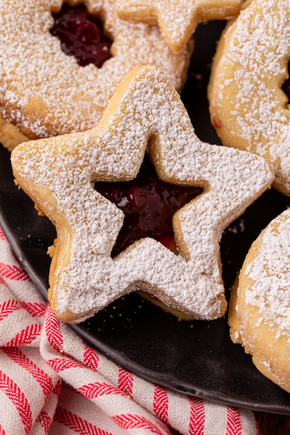 close up look of a star shaped Linzer cookies on a black plate