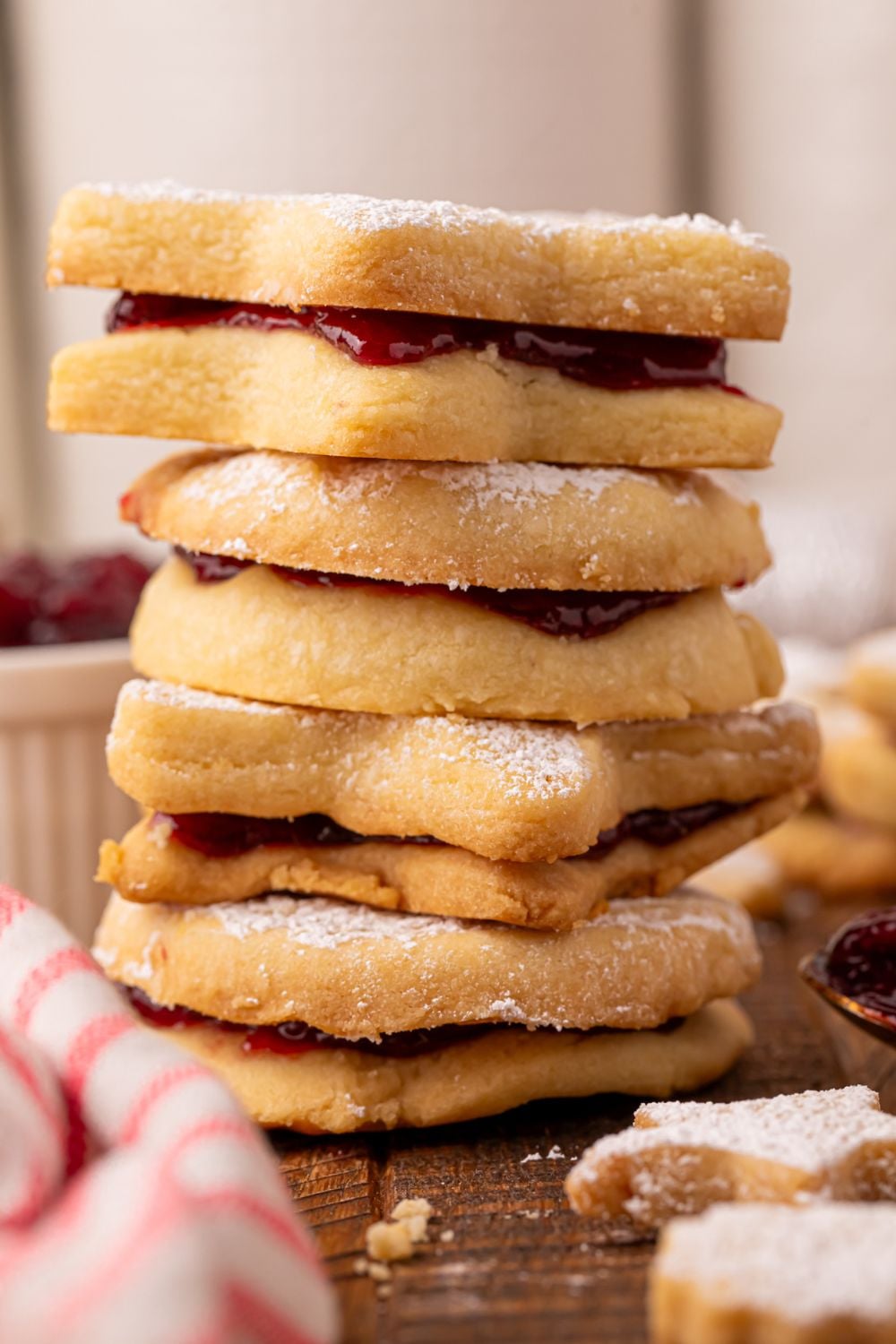 stack of Linzer cookies on a table with a striped towel to side on table