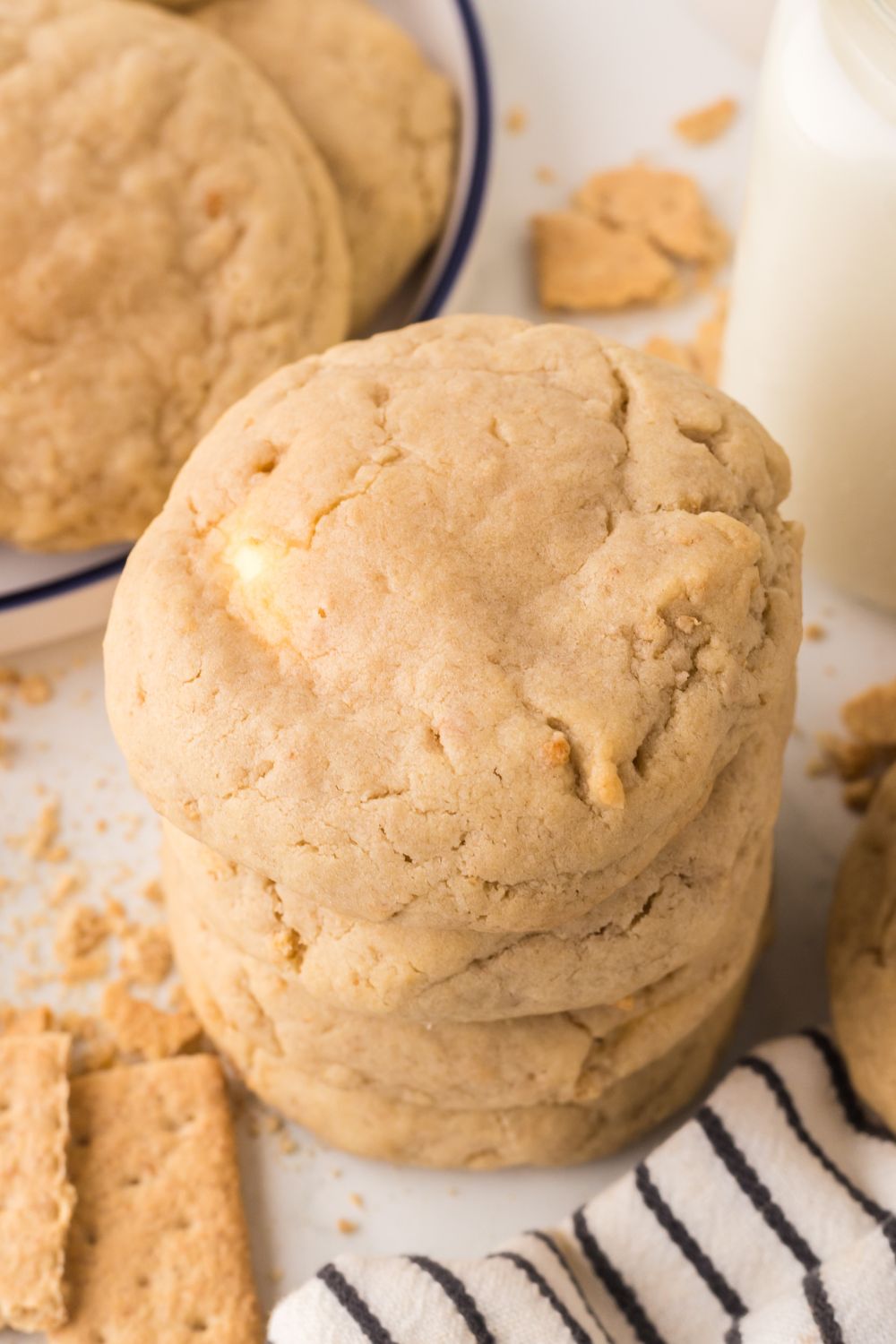 New York cheesecake cookies in a stack with more on a plate with a bottle of milk to the side 