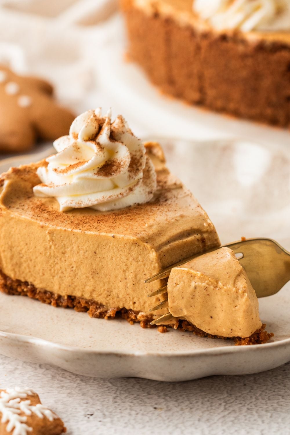 slice of No Bake Gingerbread Cheesecake on plate with a bite being cut out of it 