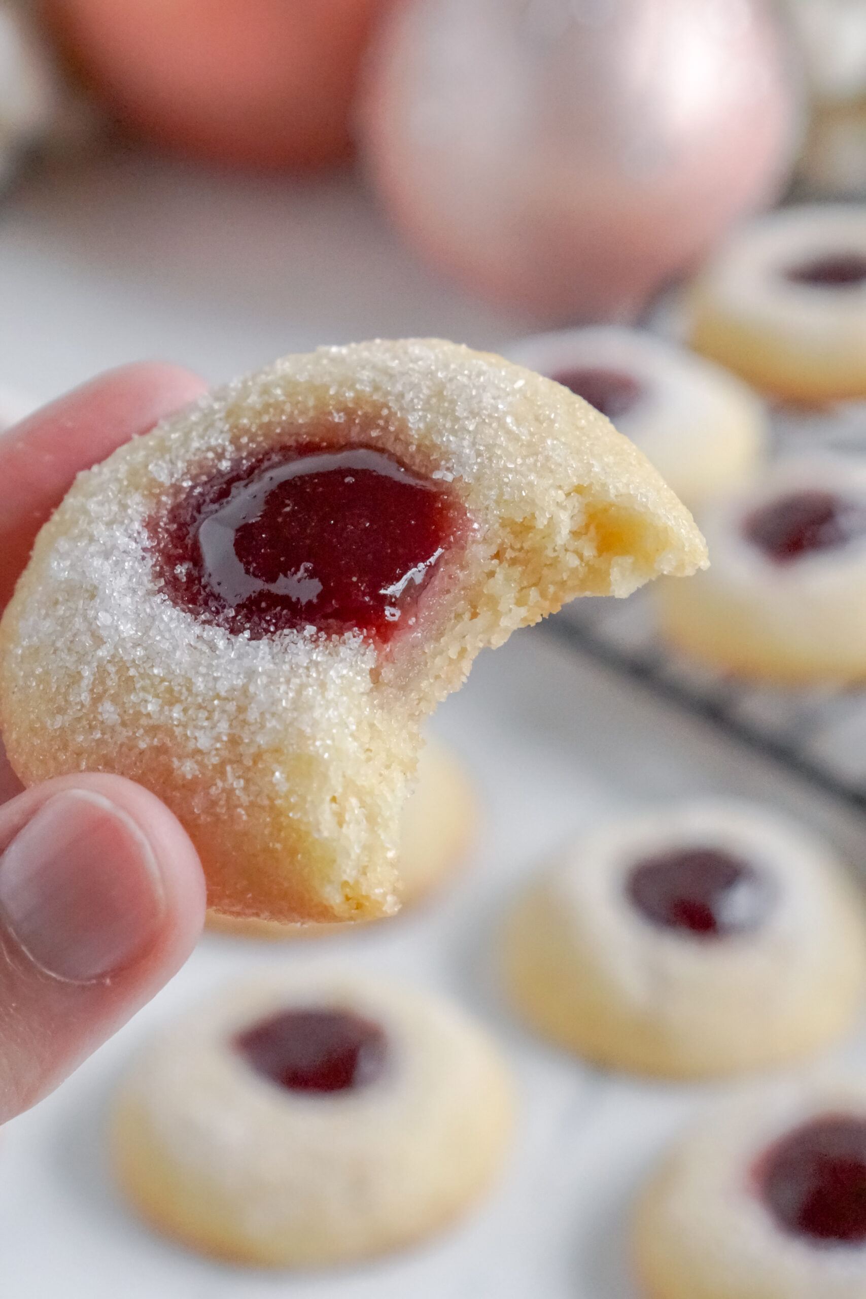 Raspberry Thumbprint Cookie with a bite missing being held up