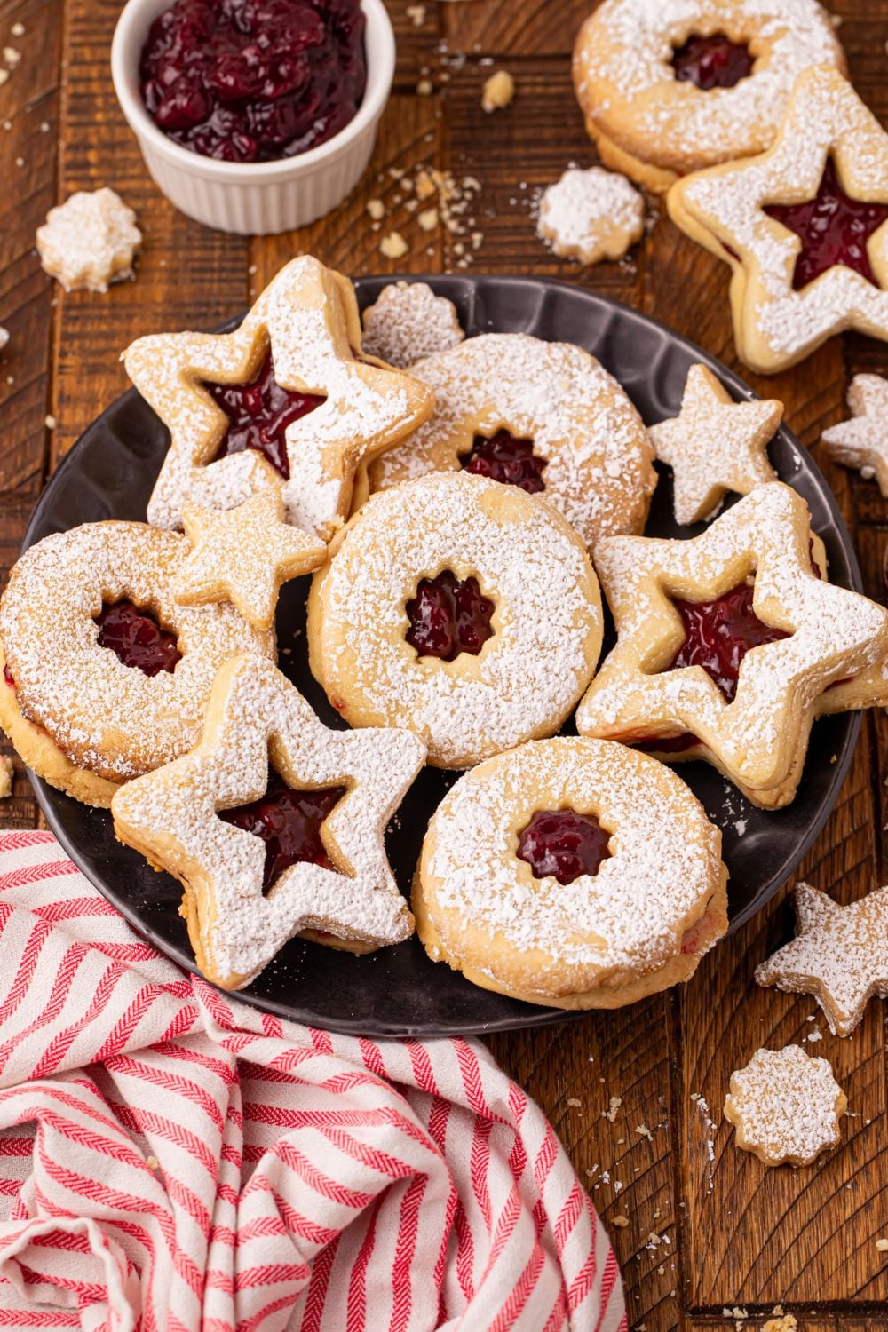 Linzer cookies spread all around table with a towel in front of the plate