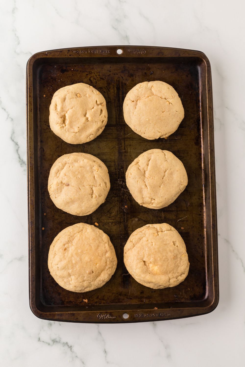 baked cheesecake stuffed cookies on marble counter on a baking sheet 
