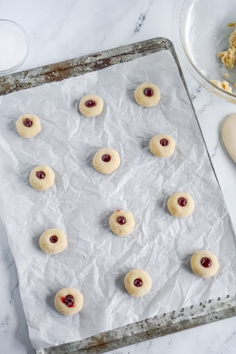 raw Raspberry Thumbprint Cookie dough placed on a baking sheet with parchment paper