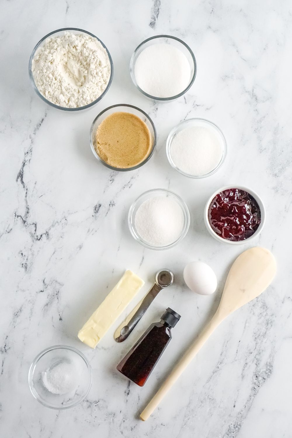ingredients to make raspberry thumbprint cookies in single serve containners on marble counter