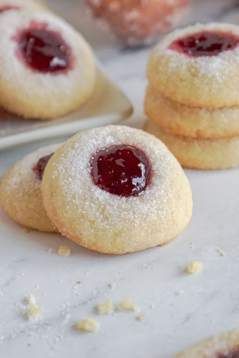 Raspberry Thumbprint Cookies placed around the table and some cookies are in a stack