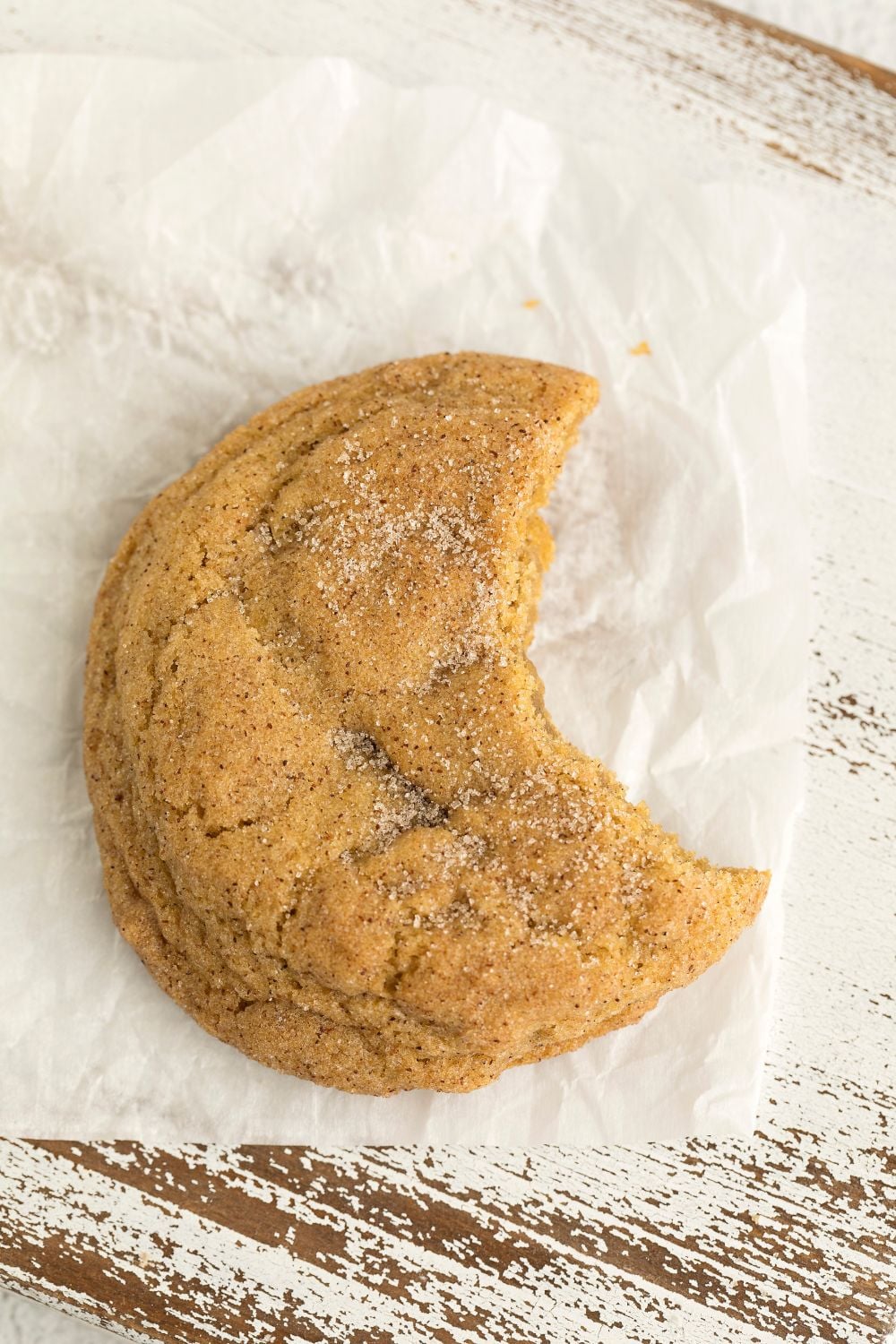 a pumpkin snickerdoodle sitting on table with a bite taken out of it 