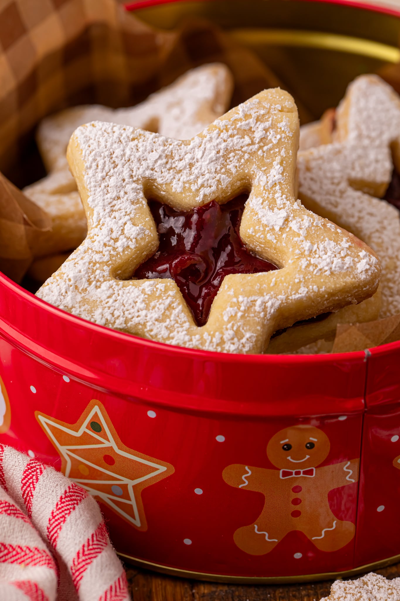 Easy Linzer Cookies with Jam Filling up close in a christmas cookie tin