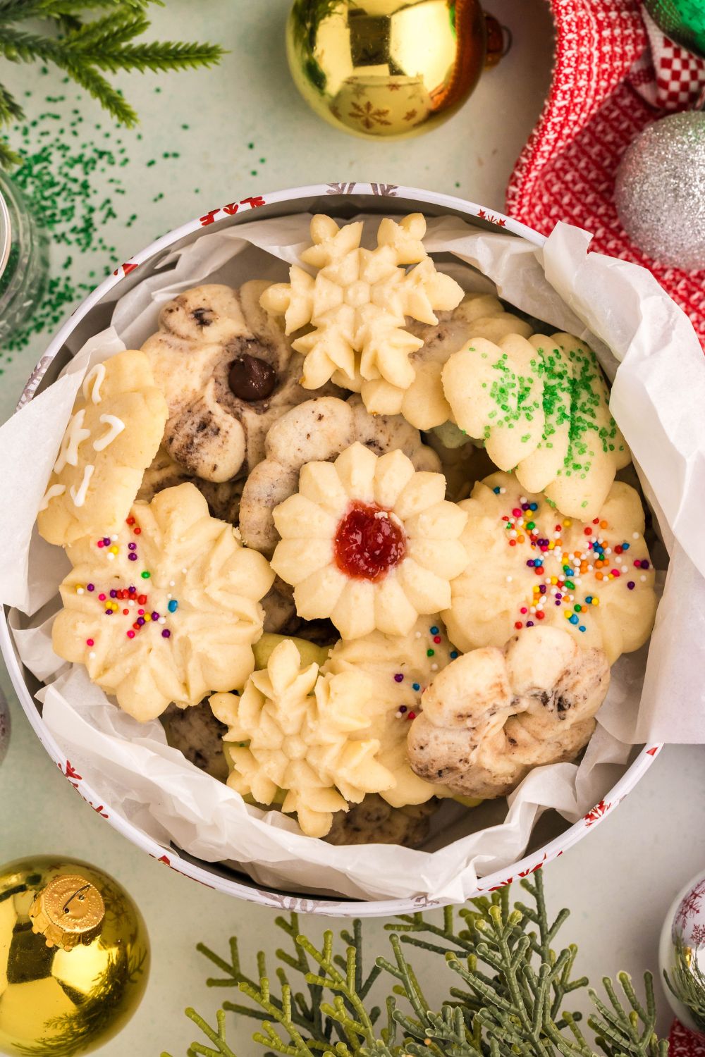 looking down on table with ornaments and a tin full of Spritz Christmas Cookies