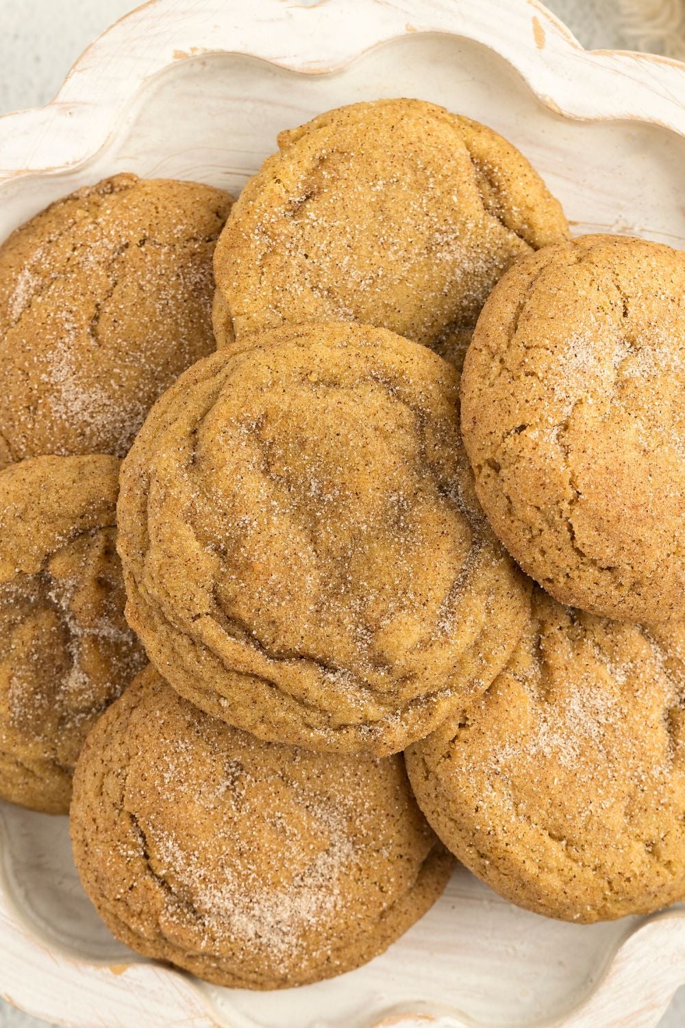 Pumpkin Snickerdoodle Cookies piled on a plate sitting on a white table 