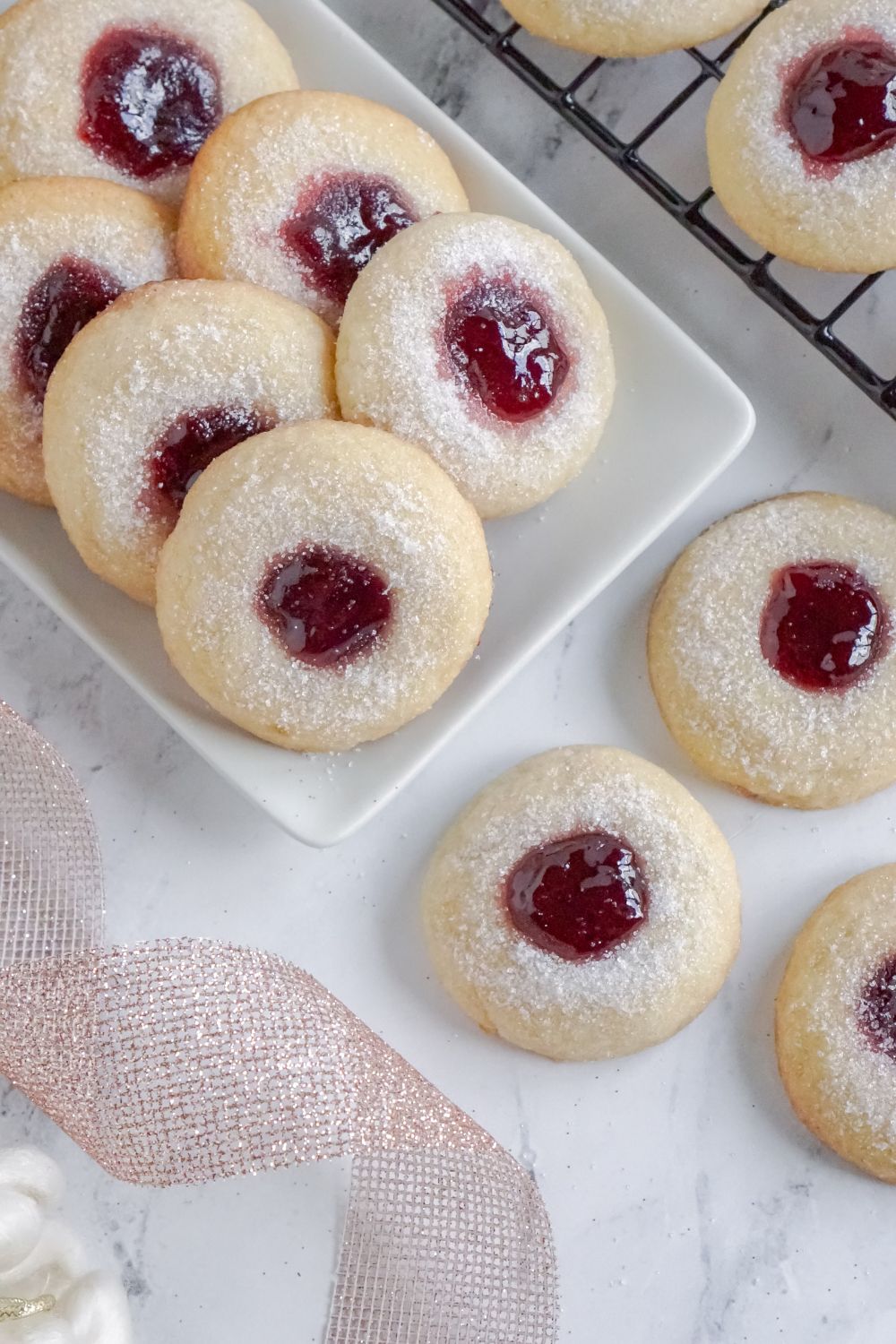 Raspberry Thumbprint Cookies on a rectangle tray with ribbon twirled to side