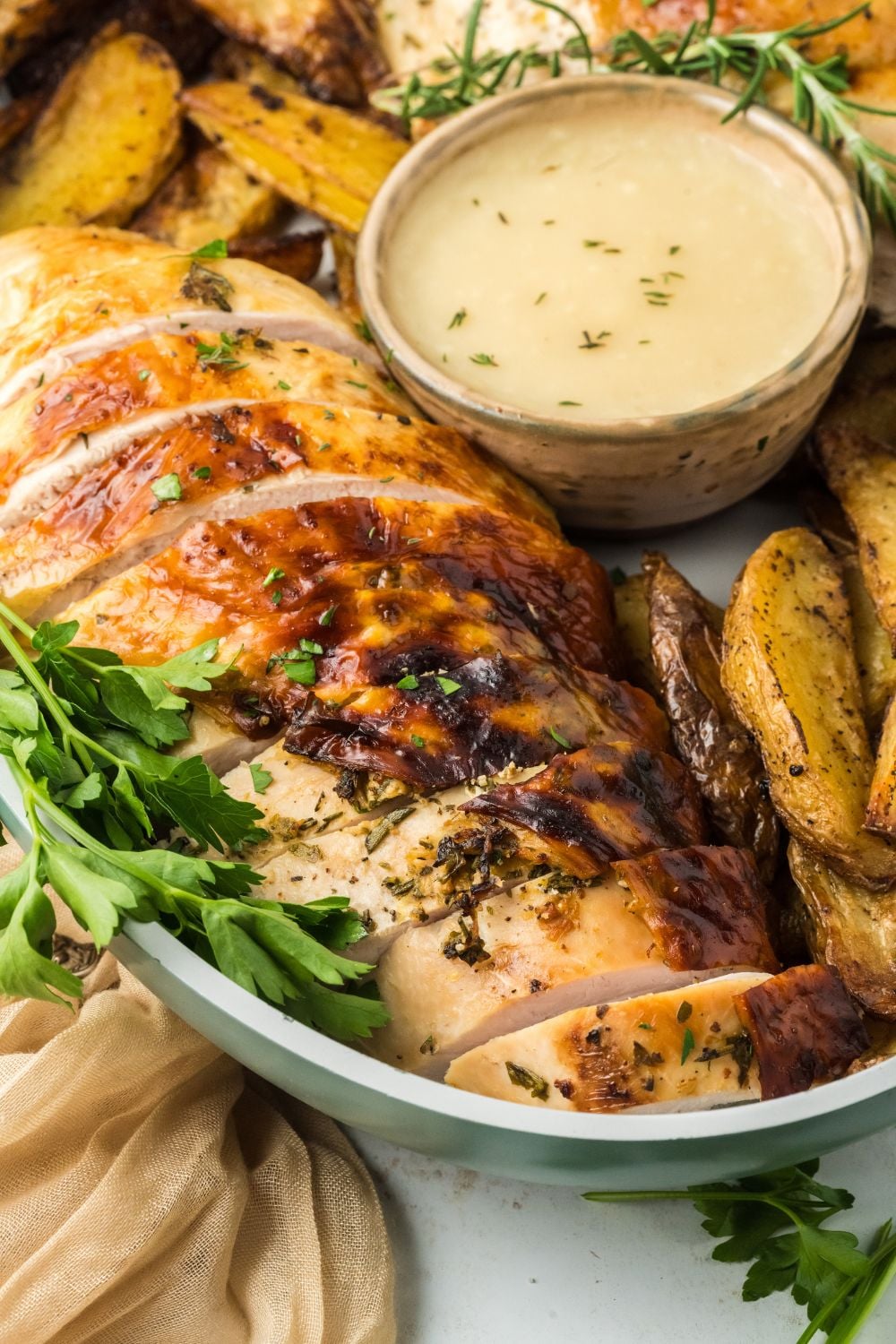 oval turkey bread with greens, potatoes, and a dipping sauce on platter on table