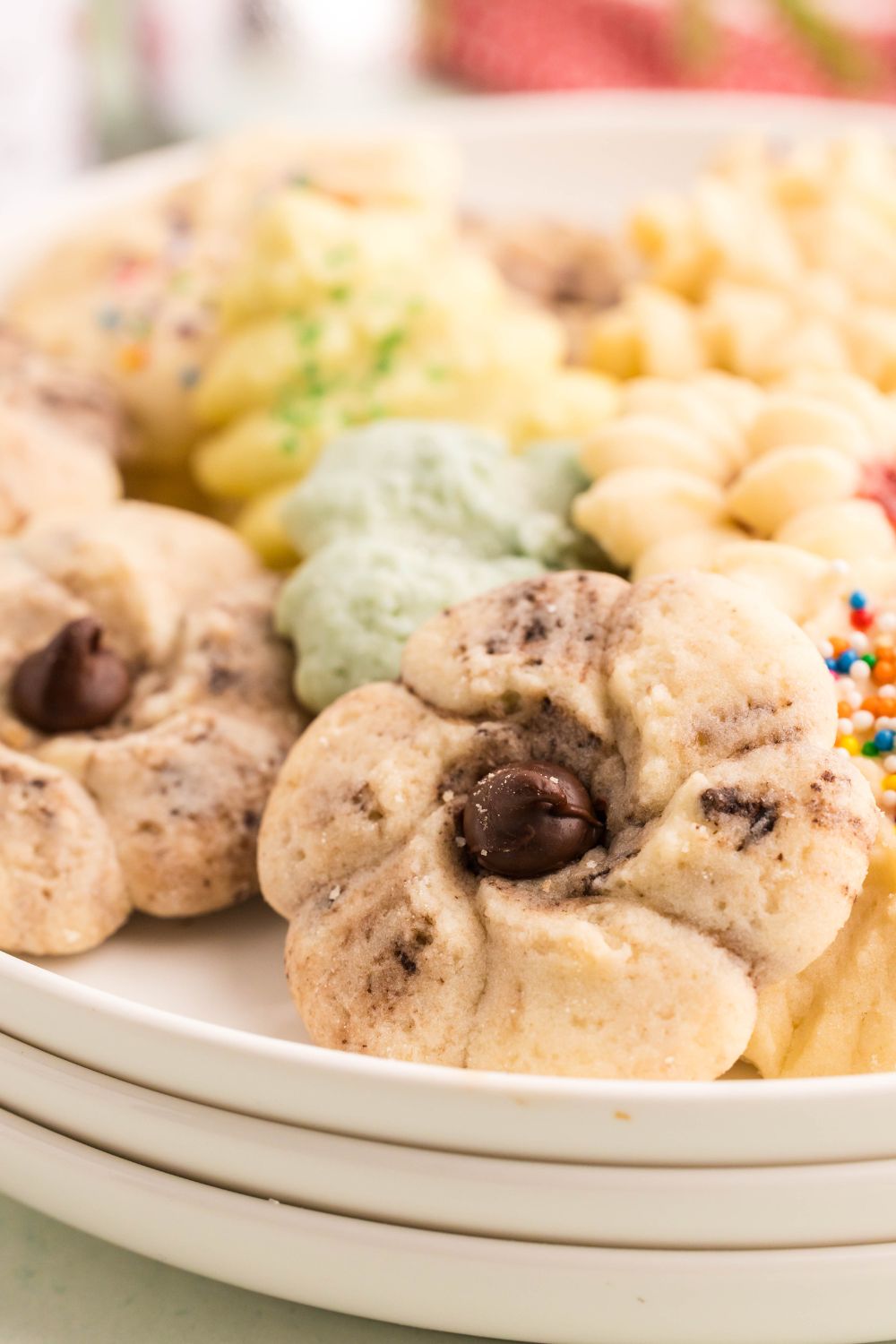 a stack of plate with a mix of Spritz Christmas Cookies