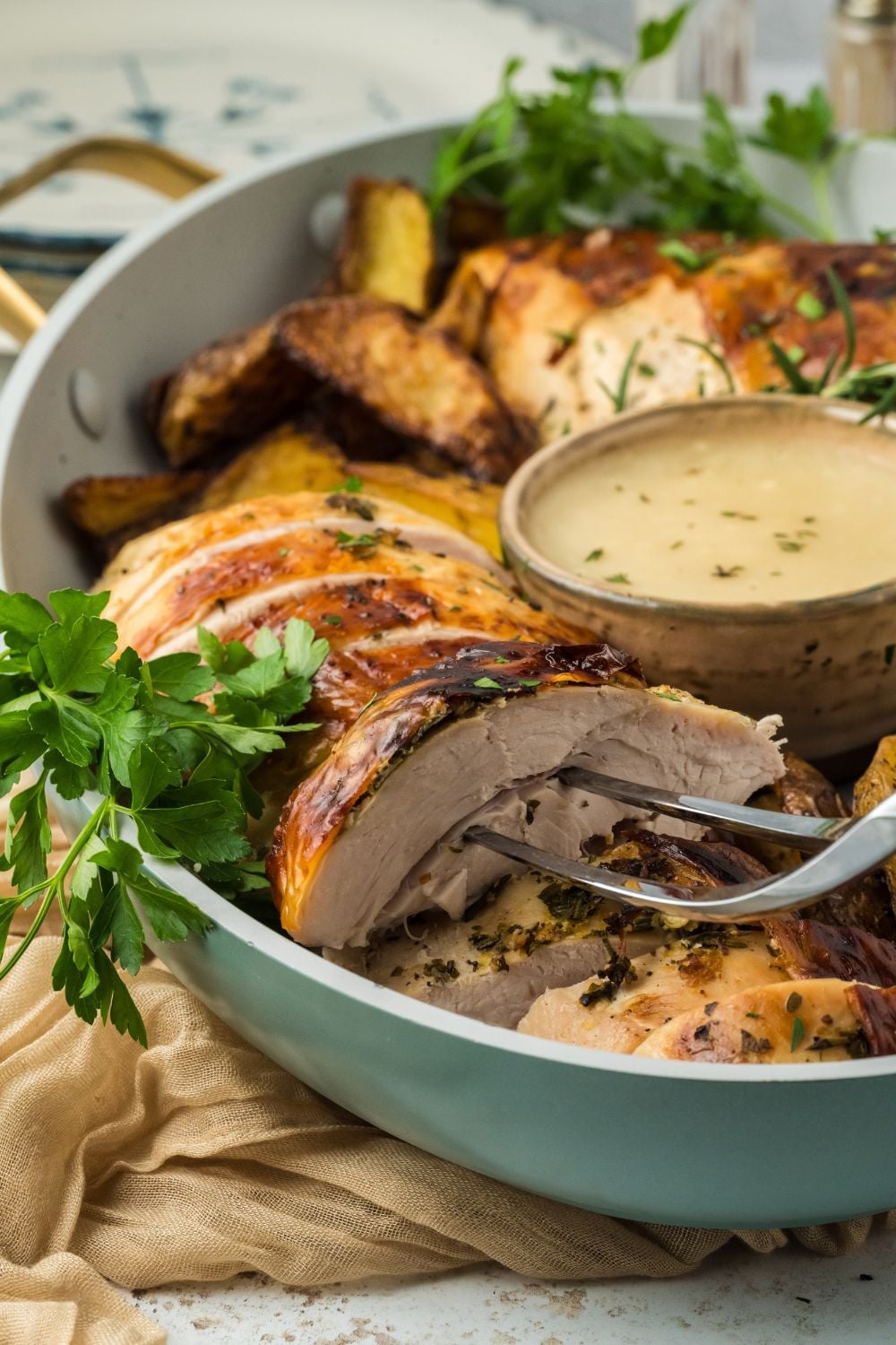 sliced Roasted Turkey Breast in a bowl with a fork poking into a thicker slice to show how tender the turkey is