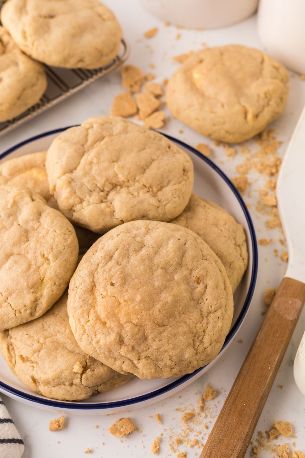 New York cheesecake cookies on a white tray, with more cookies around the table with graham cracker crumbs around the table 