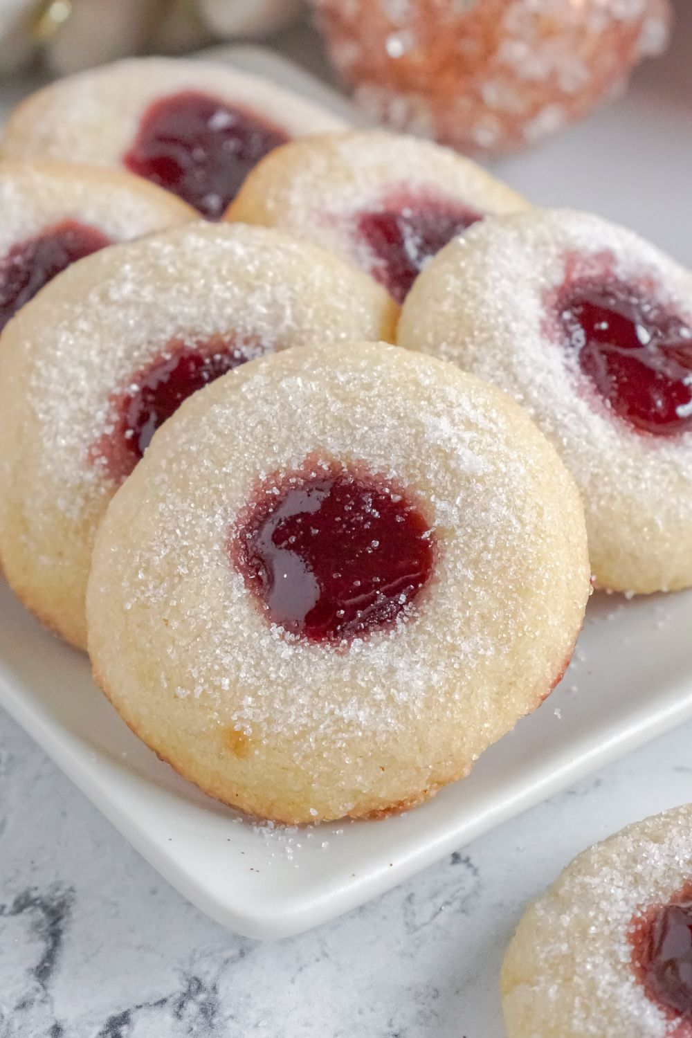 Raspberry Thumbprint Cookies on a platter on a marble counter
