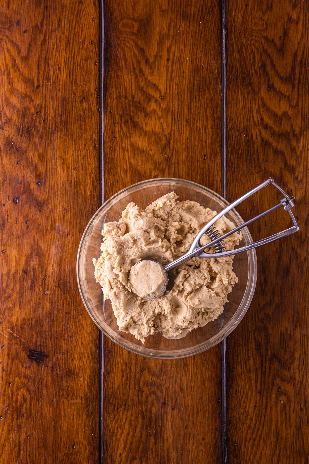 Biscoff Snickerdoodle Cookie dough in a glass bowl with a cookie scoop