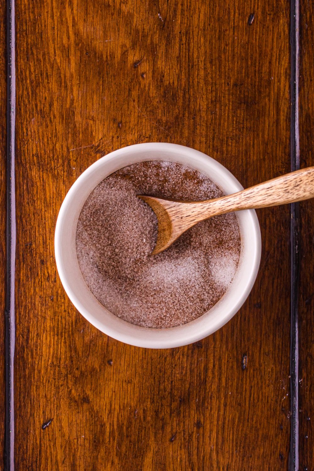 cinnamon sugar in a white bowl with a wooden spoon mixed