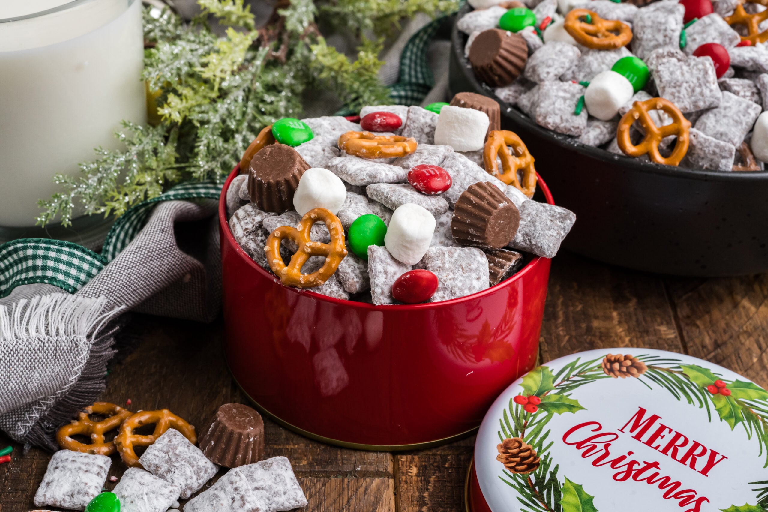 Christmas tin with Christmas Chex Mix and more puppy chow and toppings falling out of bowl