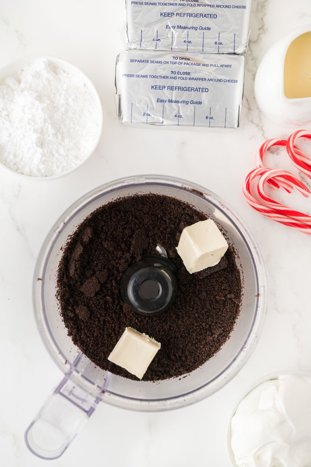 food processor with butter and crushed oreos on table