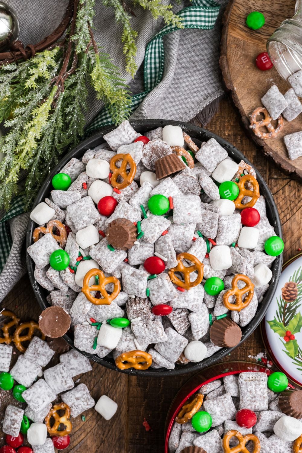 a blend of bowls of Christmas Chex Mix and a greenery around table