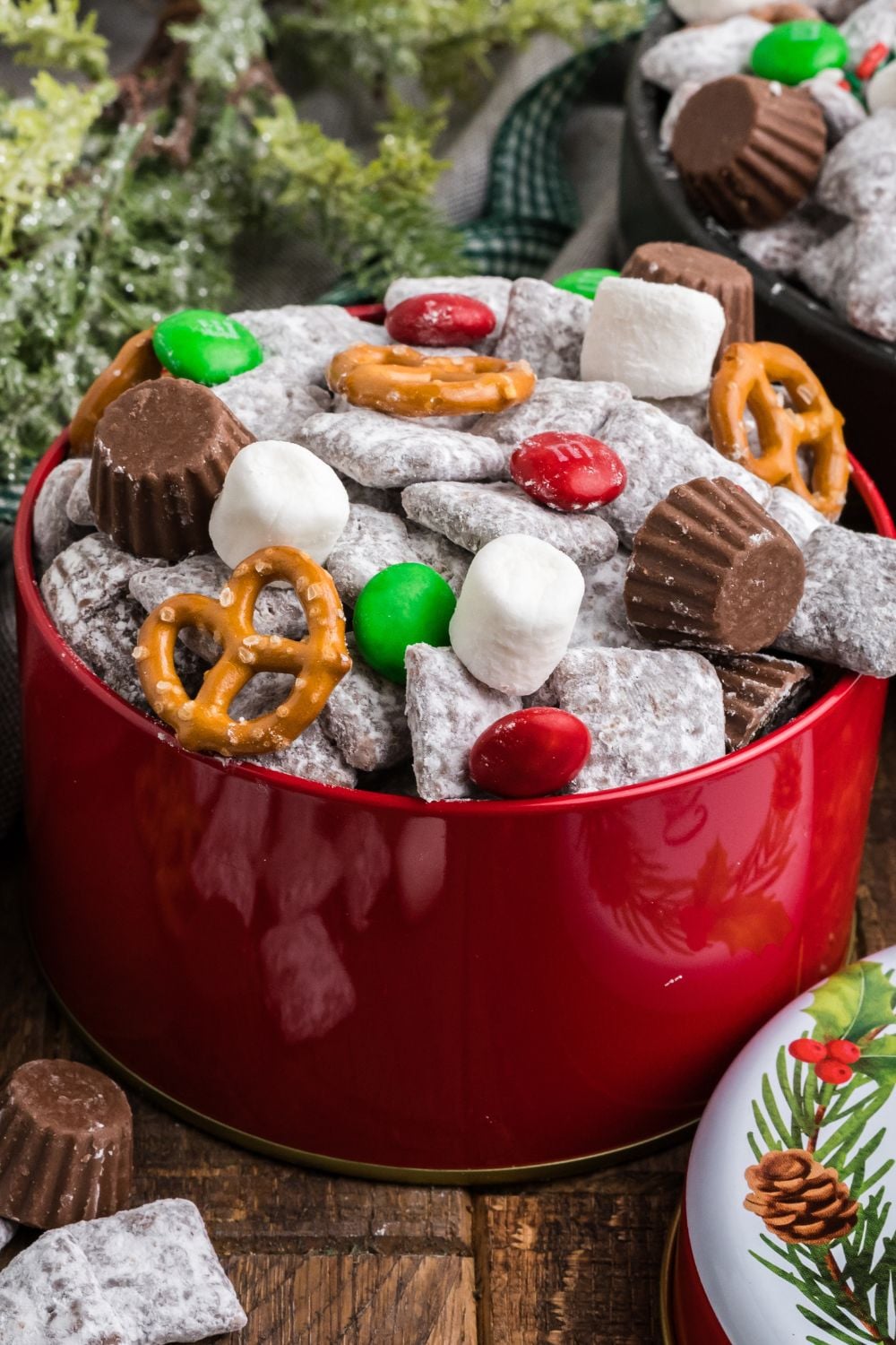Christmas snack mix for gifts in a red tin on table with lid placed to the side