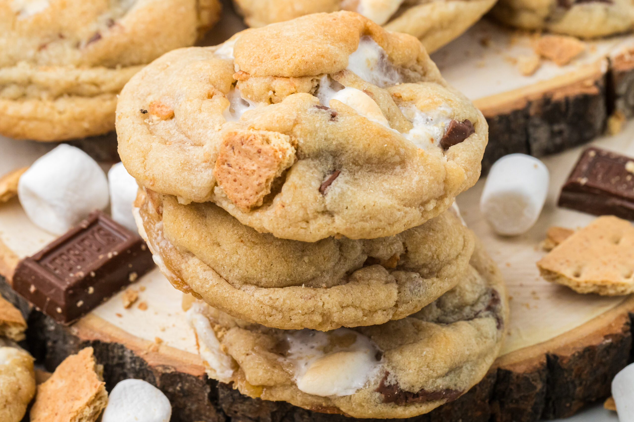 S'mores Cookies stacked on top of one another with marshmallows and chocolate bar pieces around