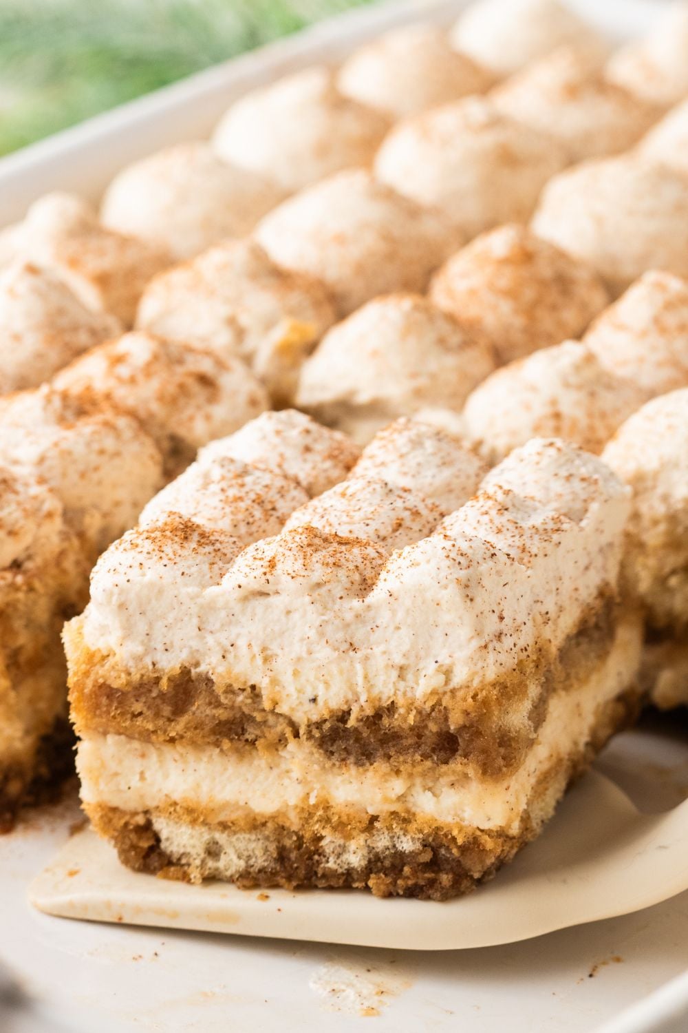a slice of eggnog tiramisu sliced and lifting out of the casserole pan