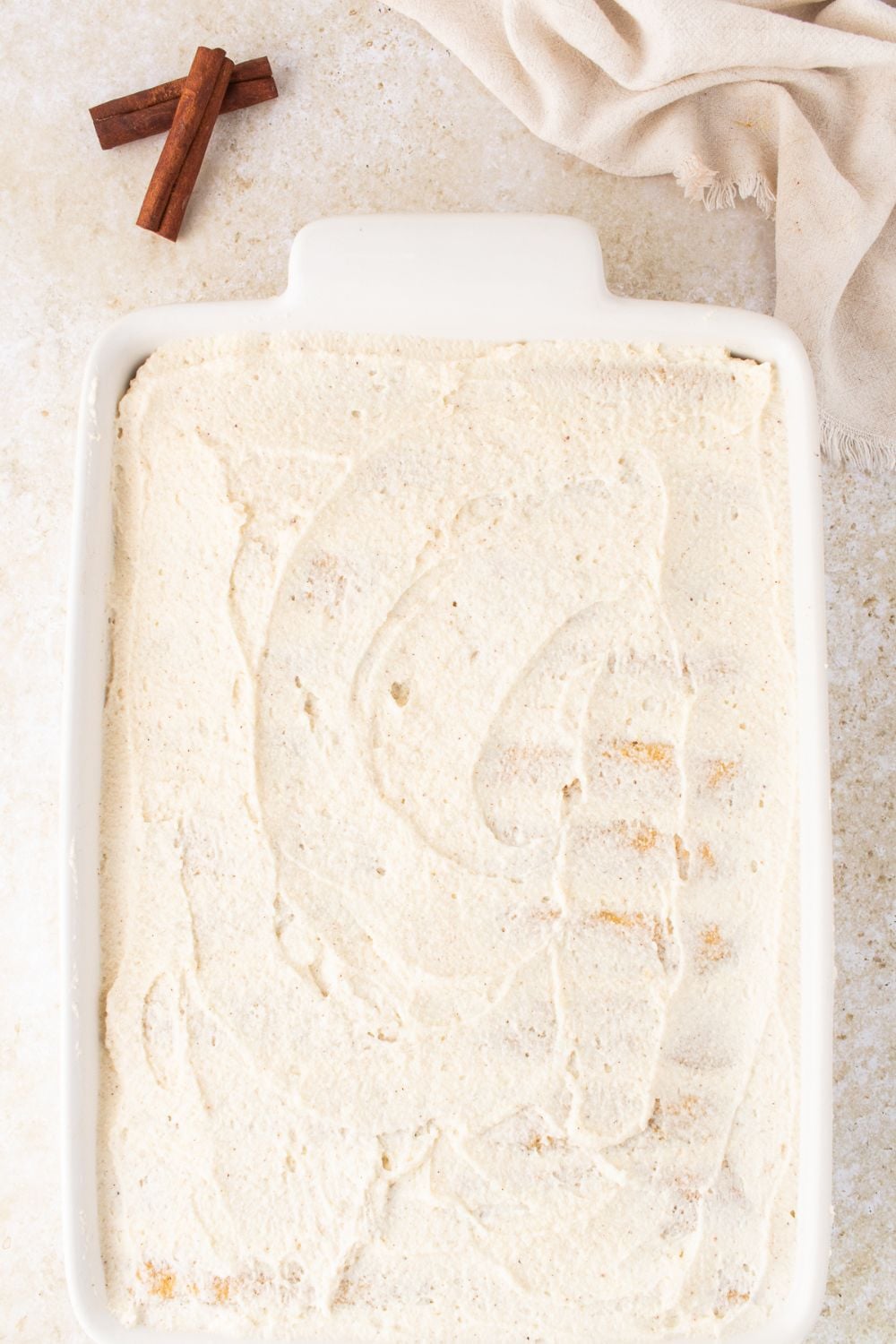 creamy topping spread on a casserole dish on table 