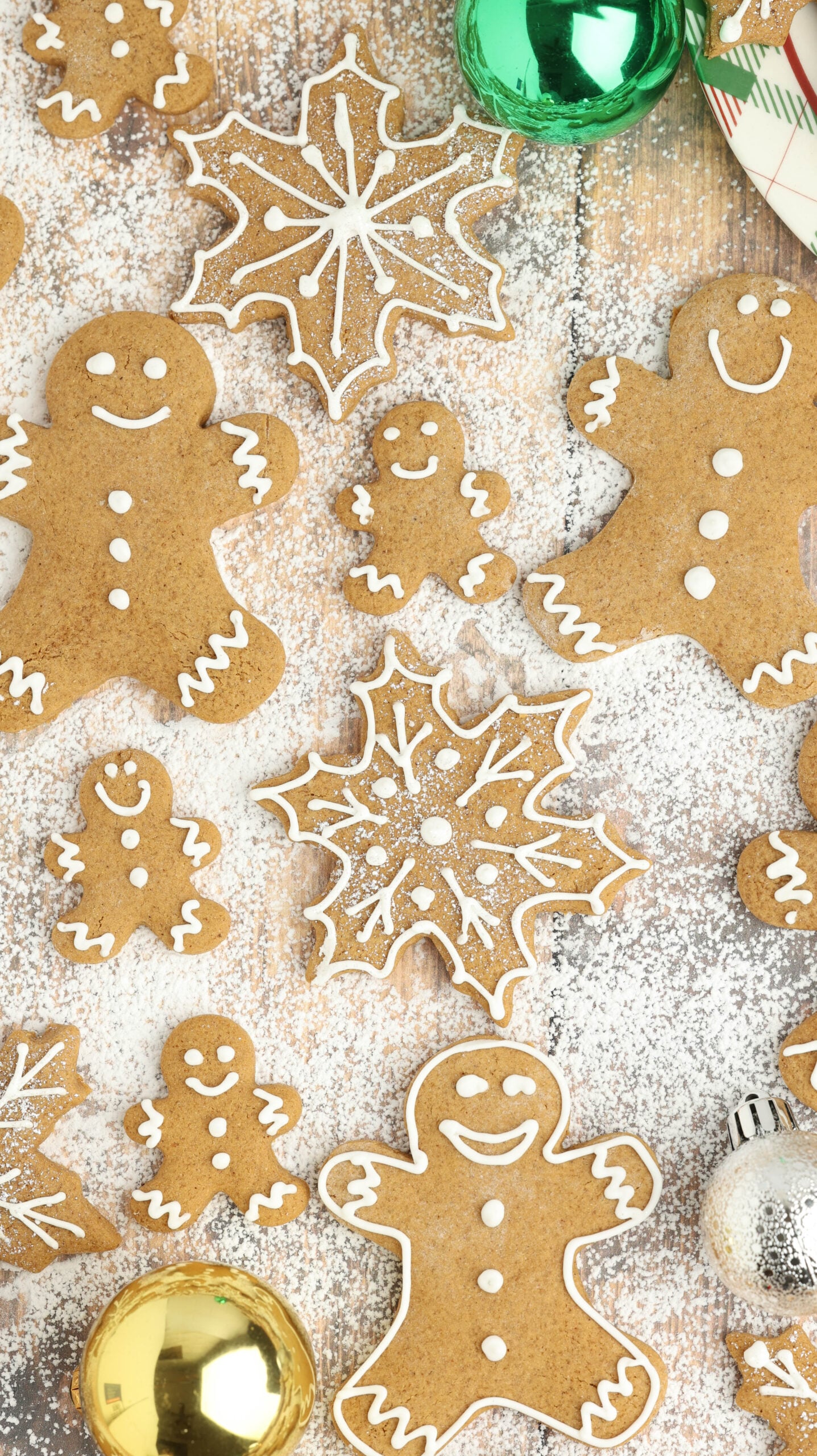 a table full of Christmas gingerbread cookies all over and different shapes laying in powdered sugar 