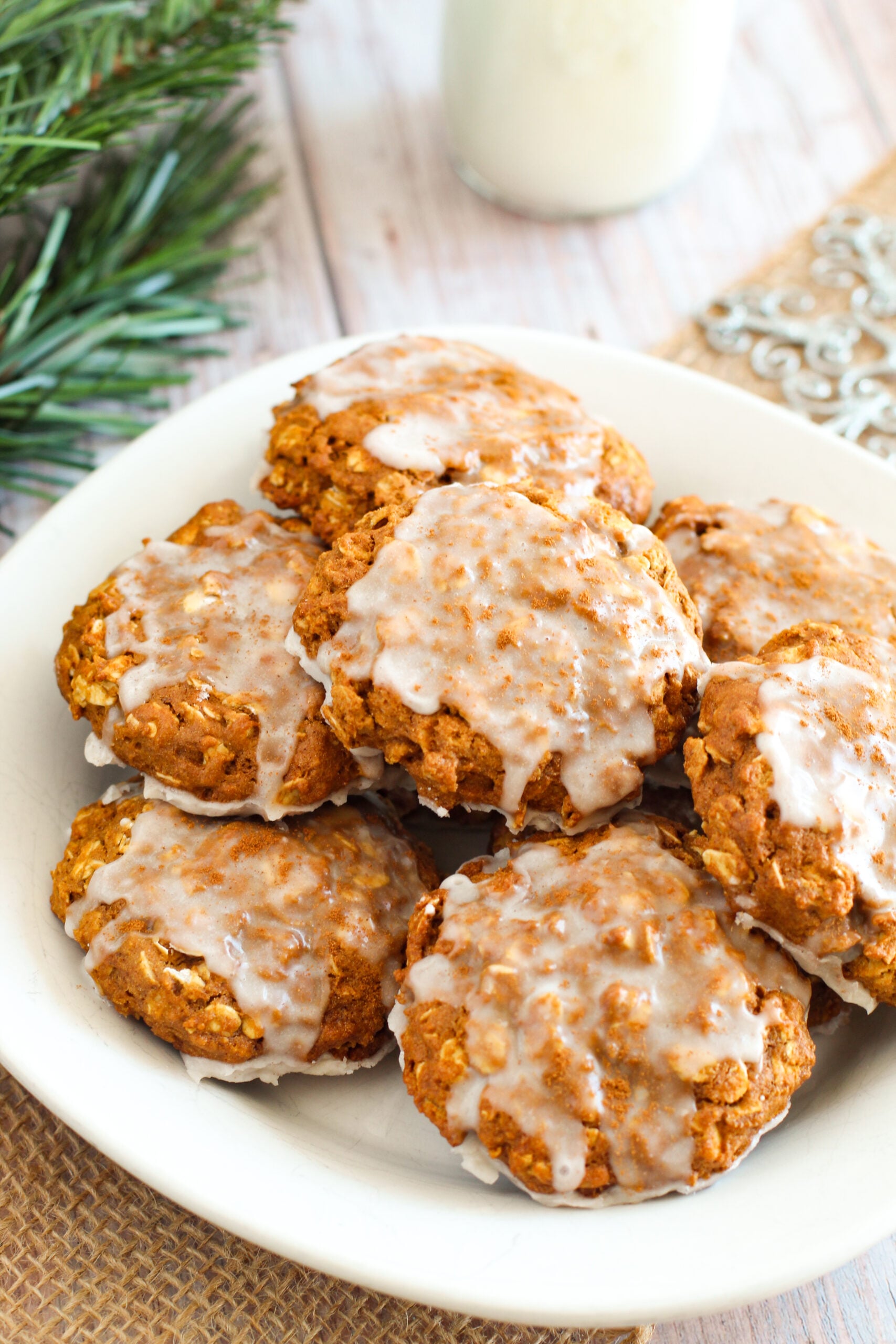 Iced Gingerbread Oatmeal Cookies on a white serving plate on a light wood table