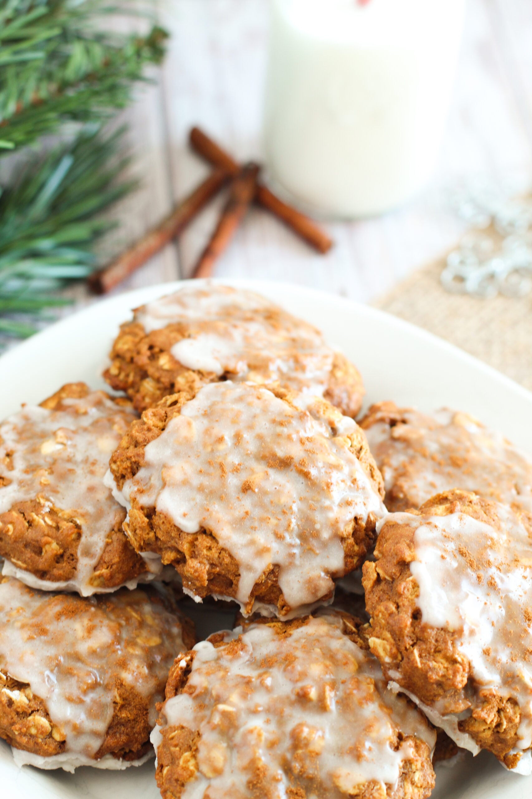 close up shit of Iced Gingerbread Oatmeal Cookies on a white serving plate on a light wood table