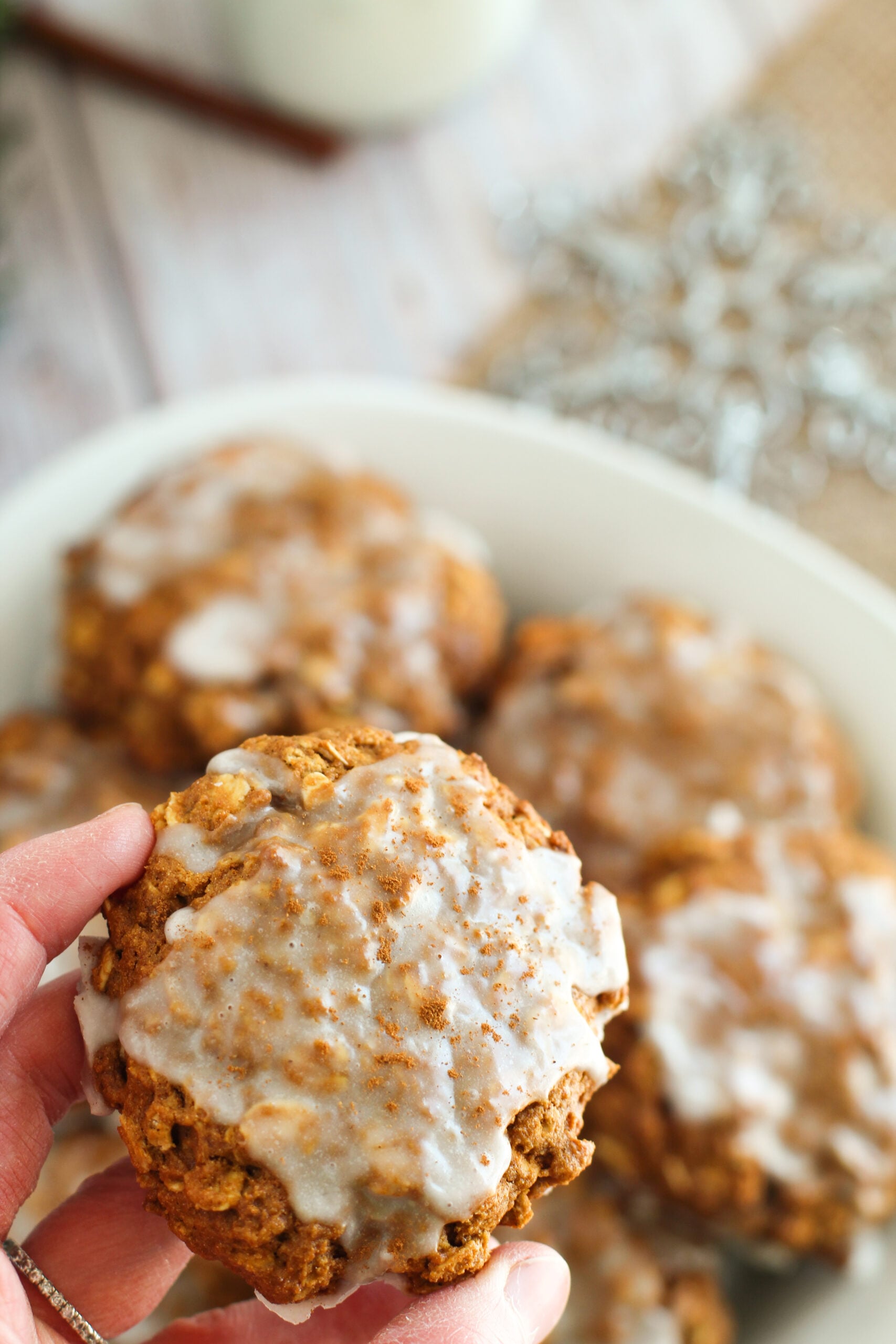 a hand holding up one Iced Gingerbread Oatmeal Cookie