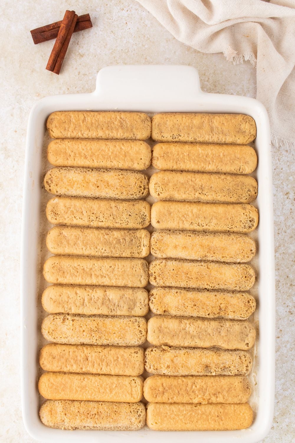 dipped ladyfingers in a casserole dish on the table 