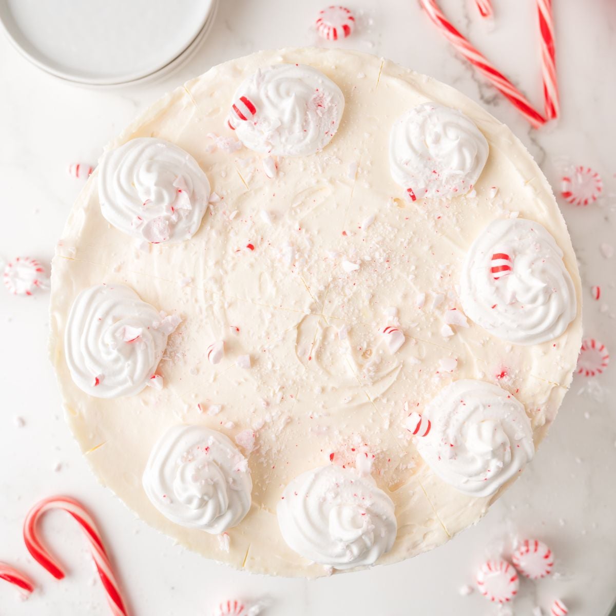 No Bake Peppermint Cheesecake on white table with candy canes around it on table 