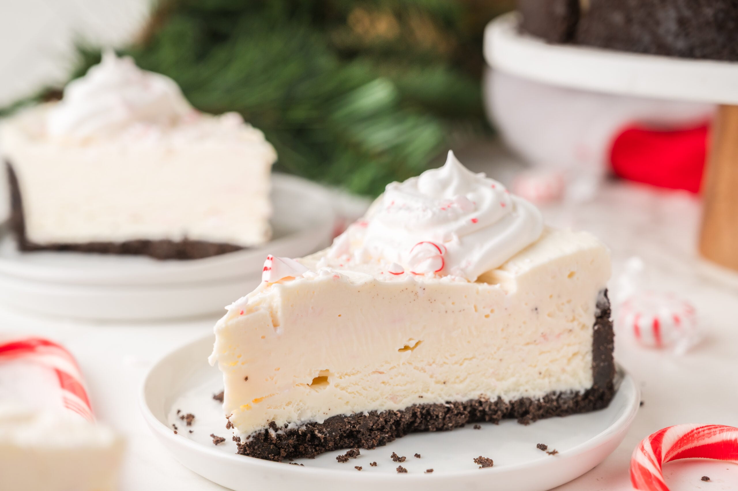 slice of No Bake Peppermint Cheesecake on a white plate with candy canes around the table 
