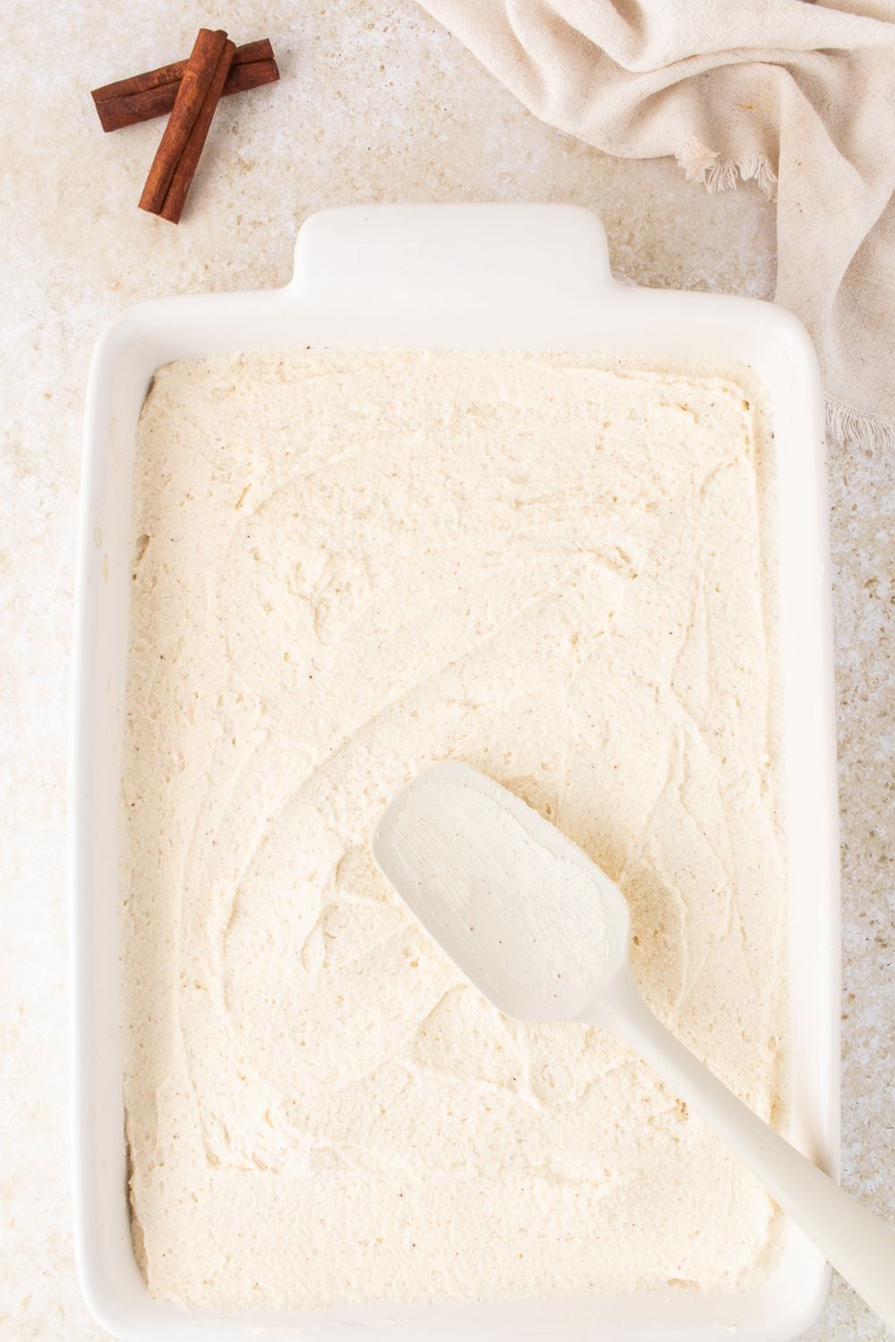 Eggnog Tiramisu being assembled with a spatula spreading around the creamy topping 