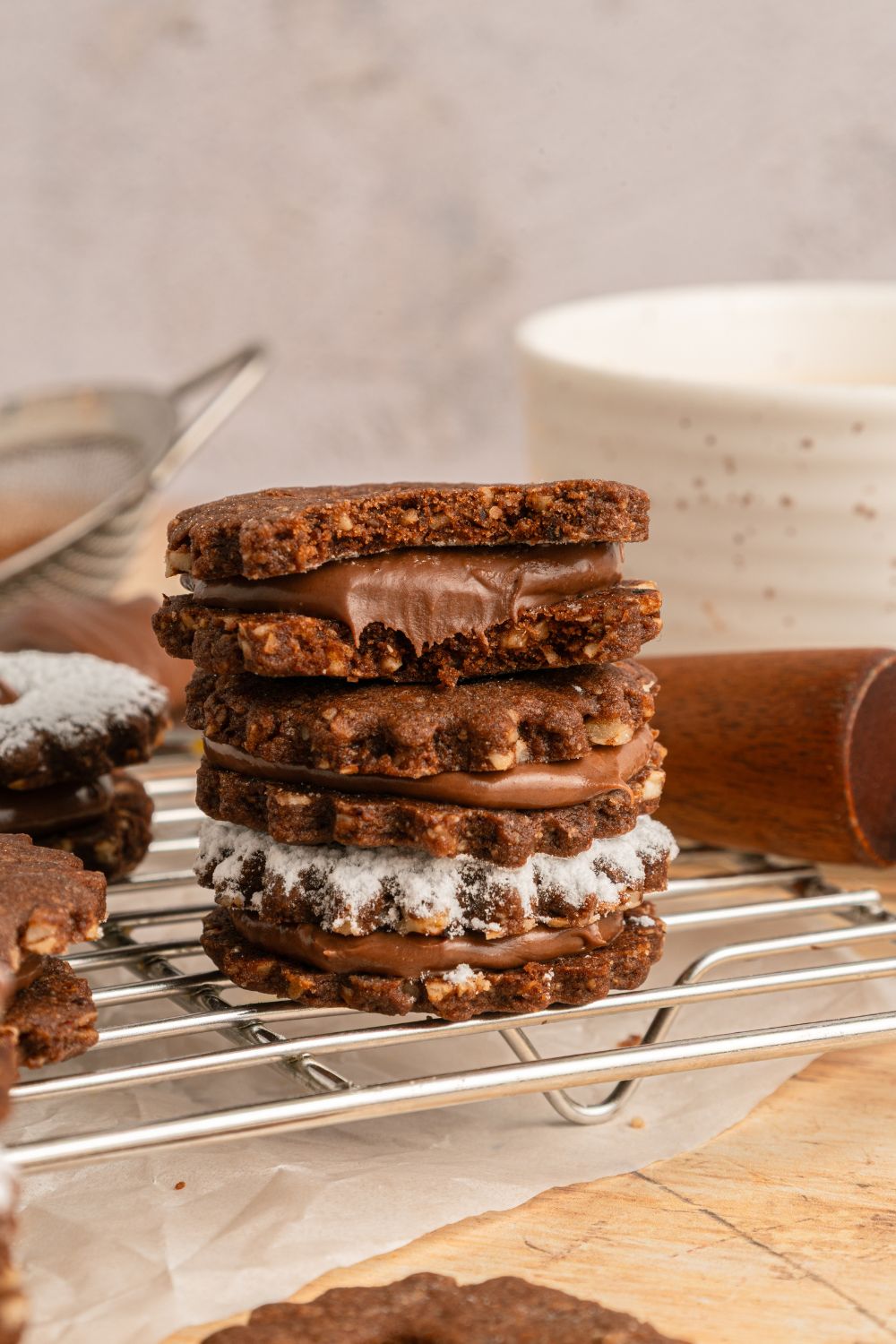 Chocolate Linzer Cookies stacked on the tray with one of the cookies with a bite taken out of it 