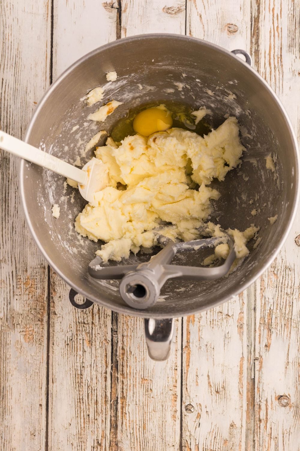 metal bowl with sugar cookie batter being mixed up with an egg in it