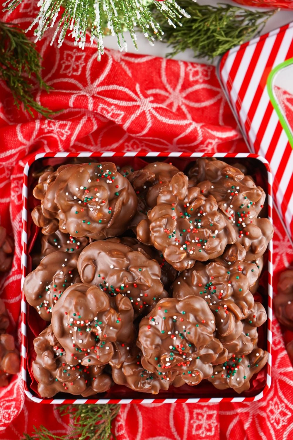 looking down on table with a tin full of Crockpot Christmas Candy on a red table