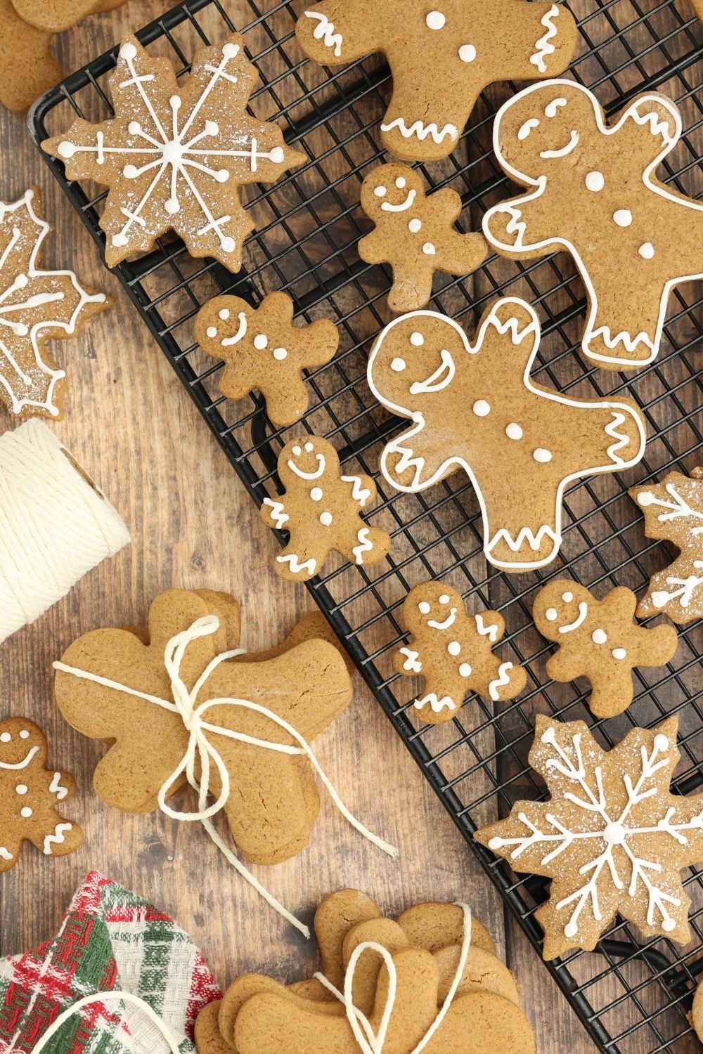 cooling rack full of different shapes of Christmas gingerbread cookies and on table with string and more for Christmas 