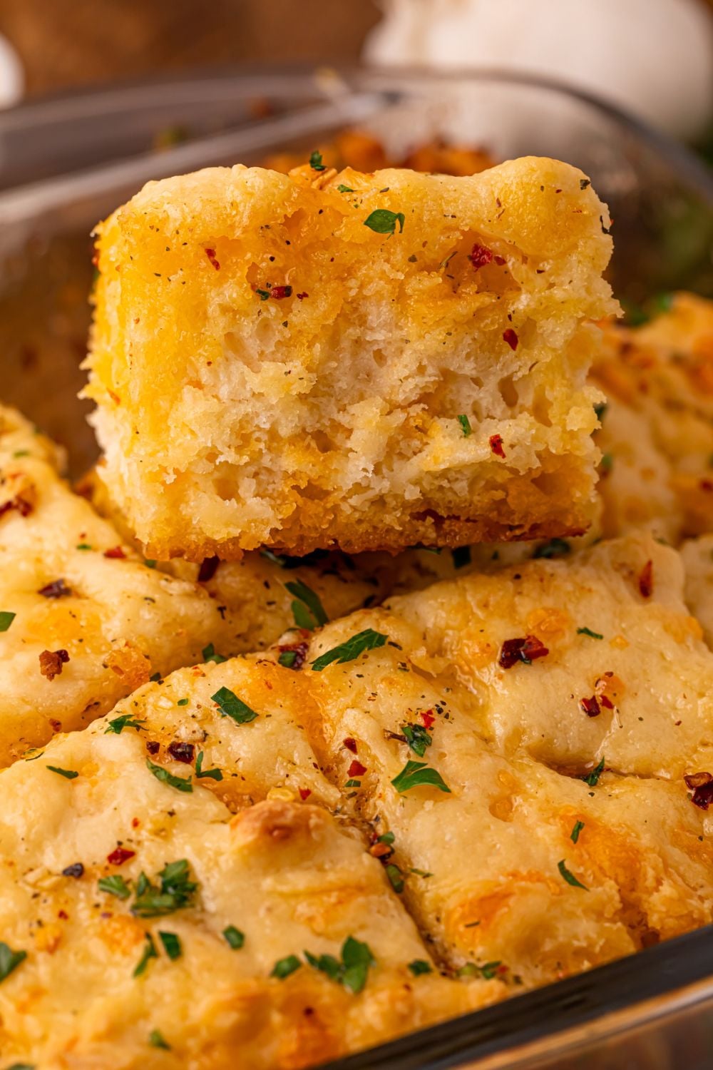 a cowboy butter biscuit being lifted out of the pan full of the rest of the biscuits