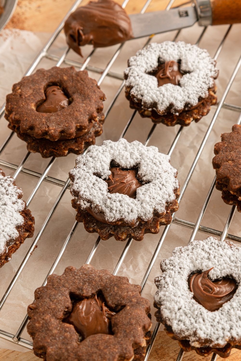 Chocolate Linzer Cookies spread out on table wit ha few of the cookies dusted with powdered sugar 