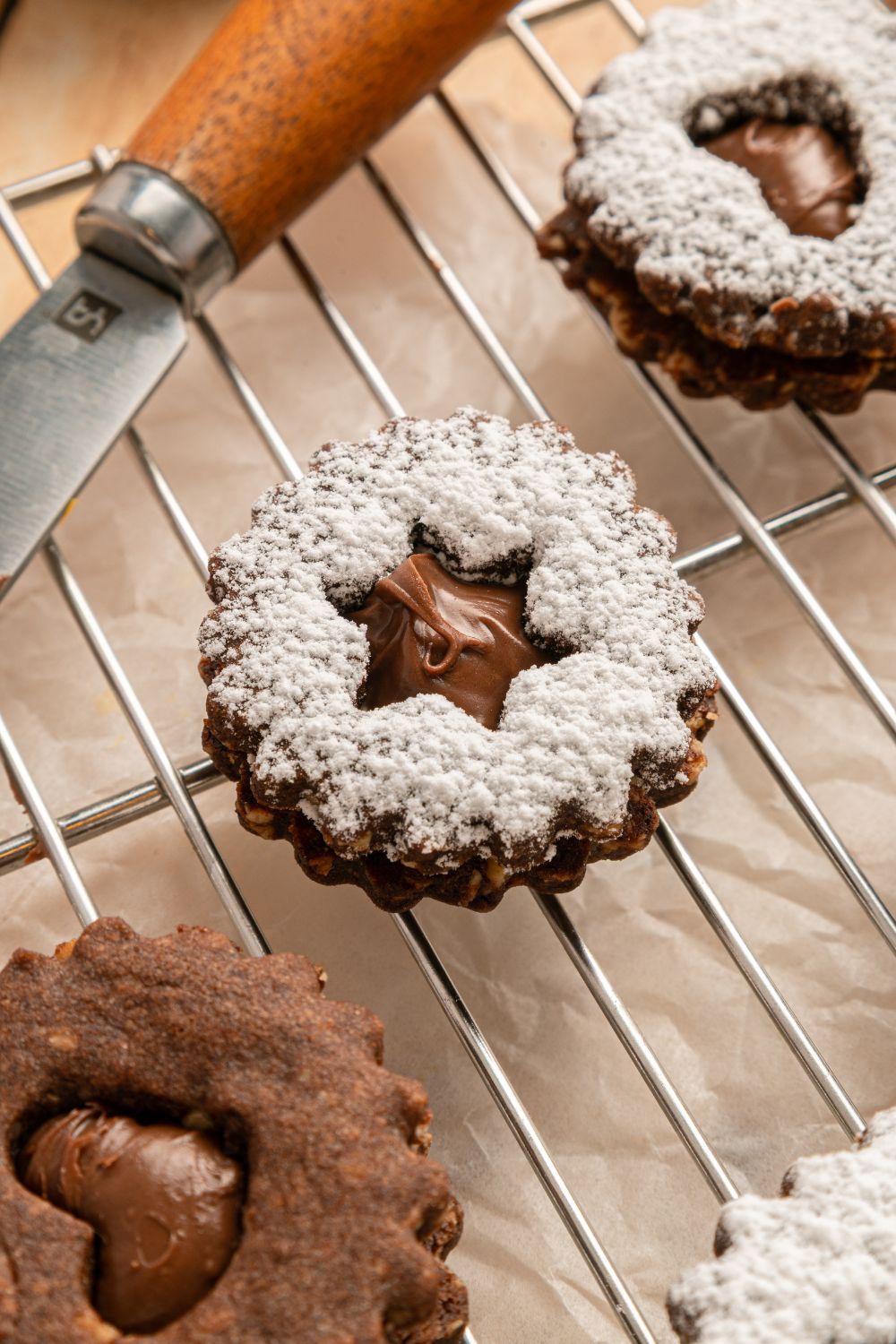 Chocolate Linzer Cookies on a cooling rack dusted with powdered sugar and covered with powdered sugar 