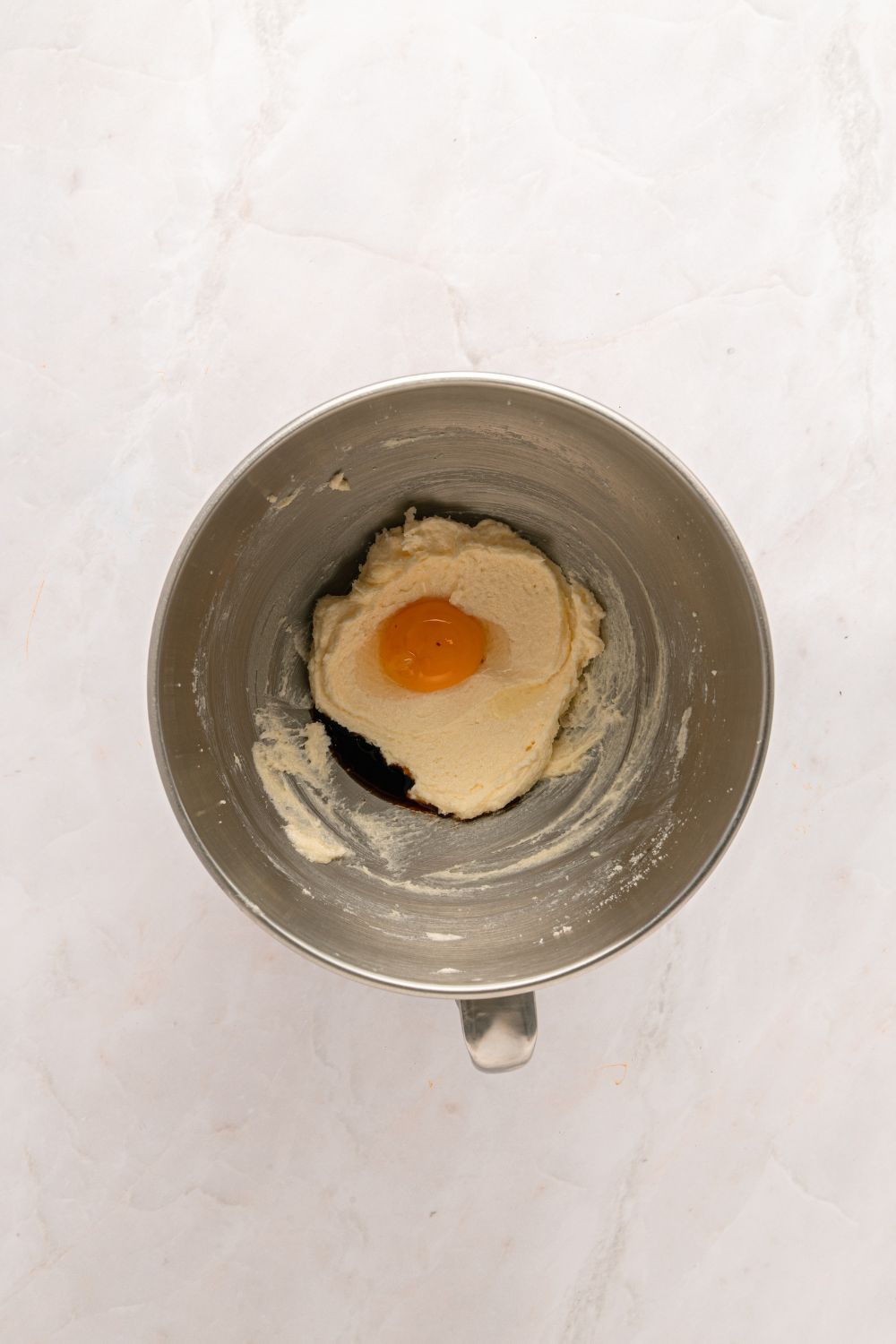 creamed butter with egg in a metal mixing bowl 